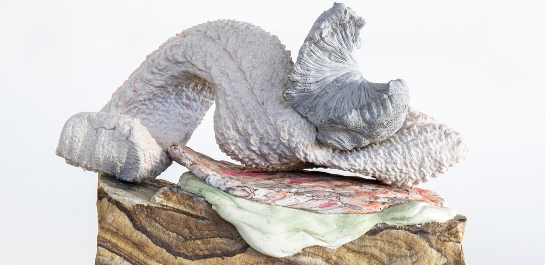 a sculpture by Lily Cox-Richard of plaster-cast mushroom sitting on an assemblage of striated stone, green ooze and fragments of woven basket